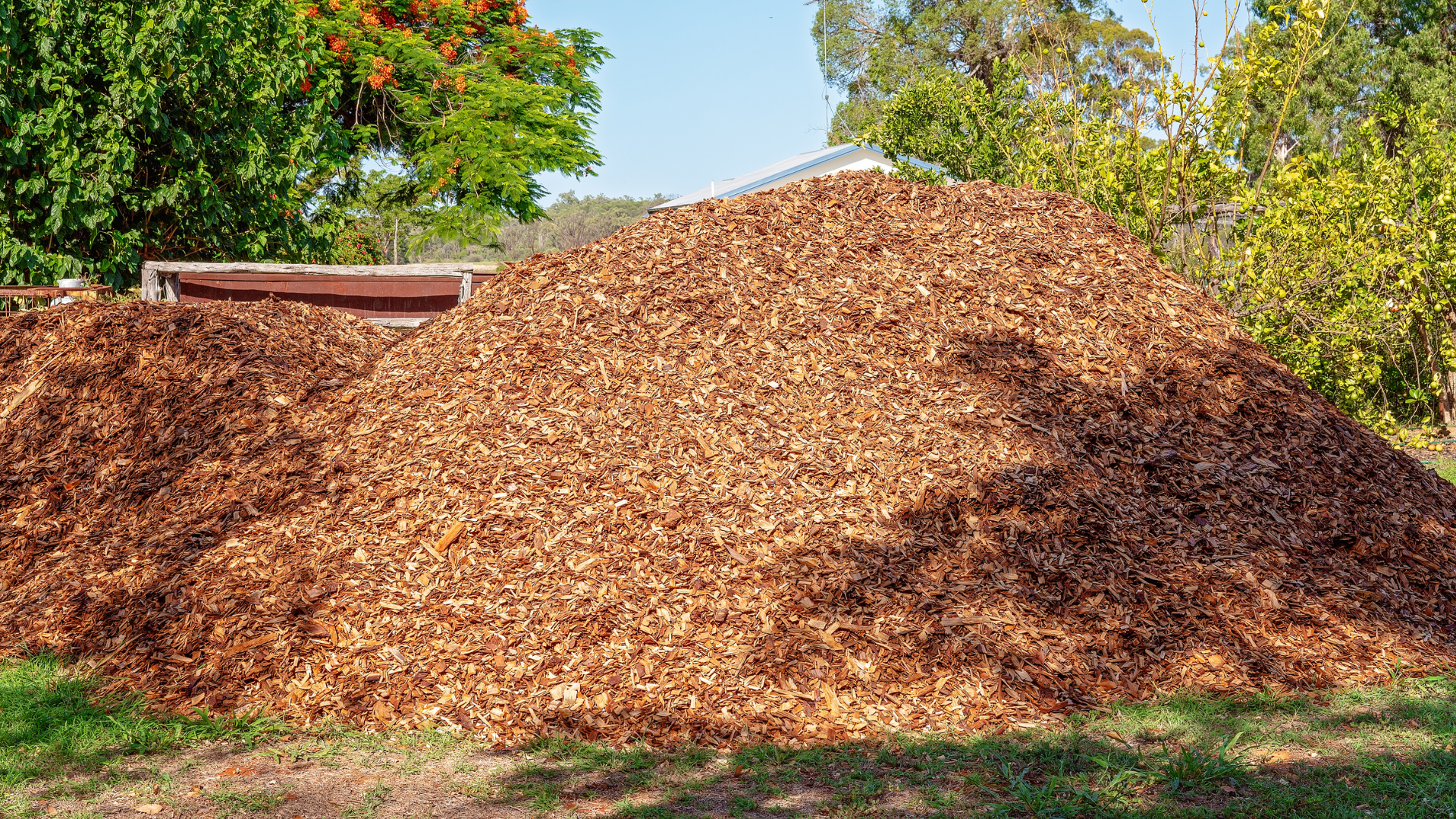 Un gros tas de copeaux de bois devant une maison.