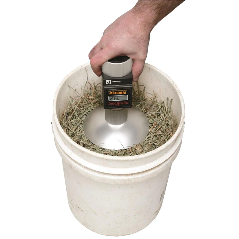 A person pressing a tester probe into a five gallon bucket of hay