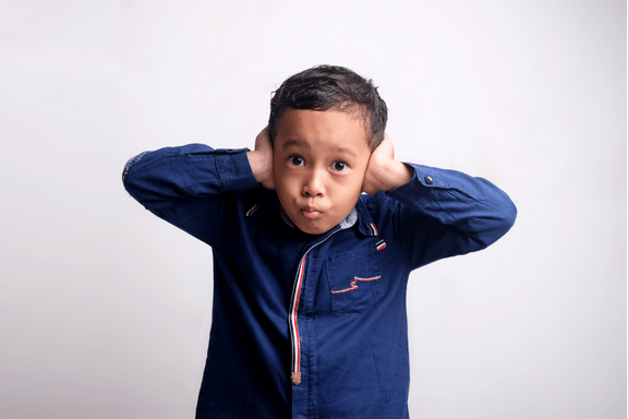 young boy holds ears in pain from ear infection