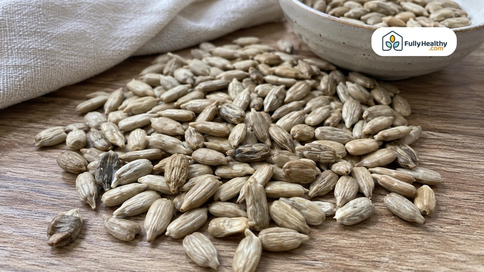 Close-up of shelled sunflower seeds scattered naturally across a wooden surface