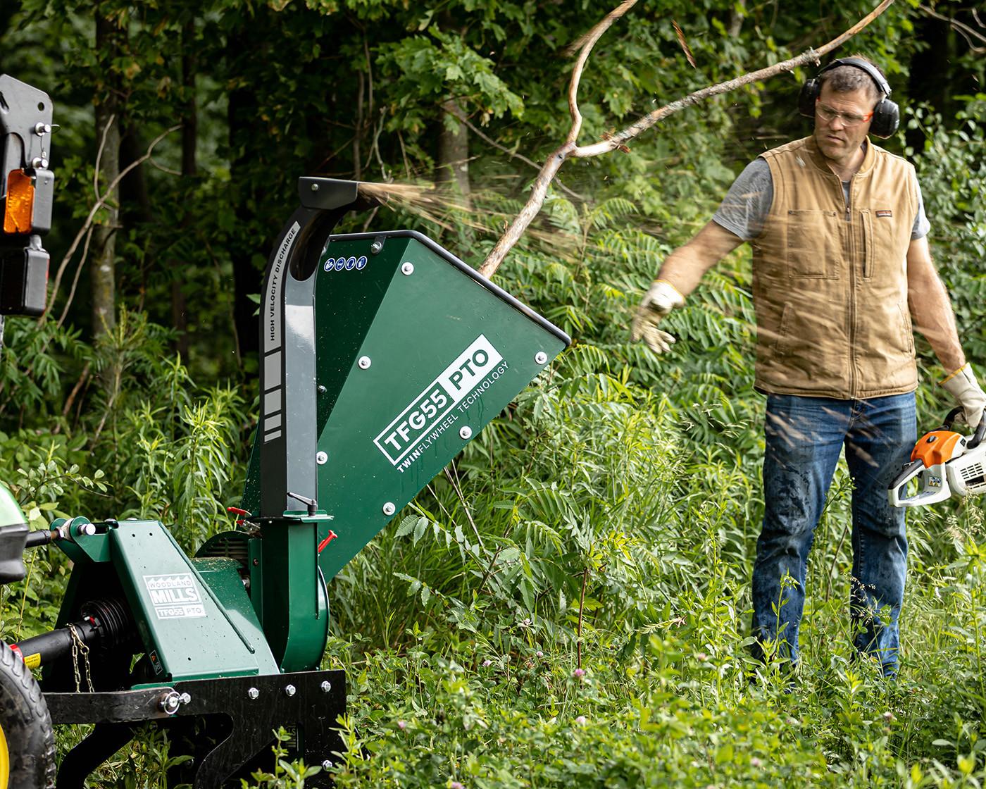 A landowner feeding material into a Woodland Mills gas-powered wood chipper.