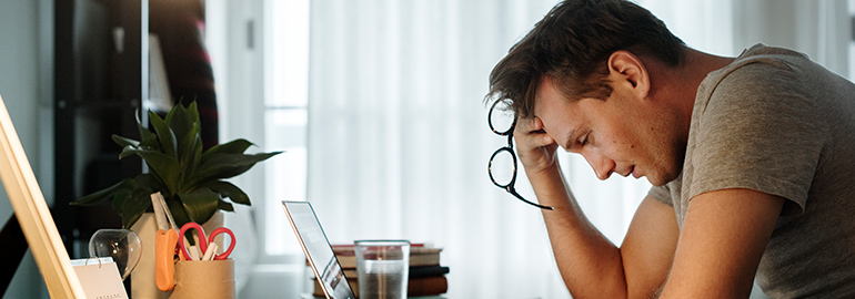 Man deep in thought, sitting at his desk with his head on his hand