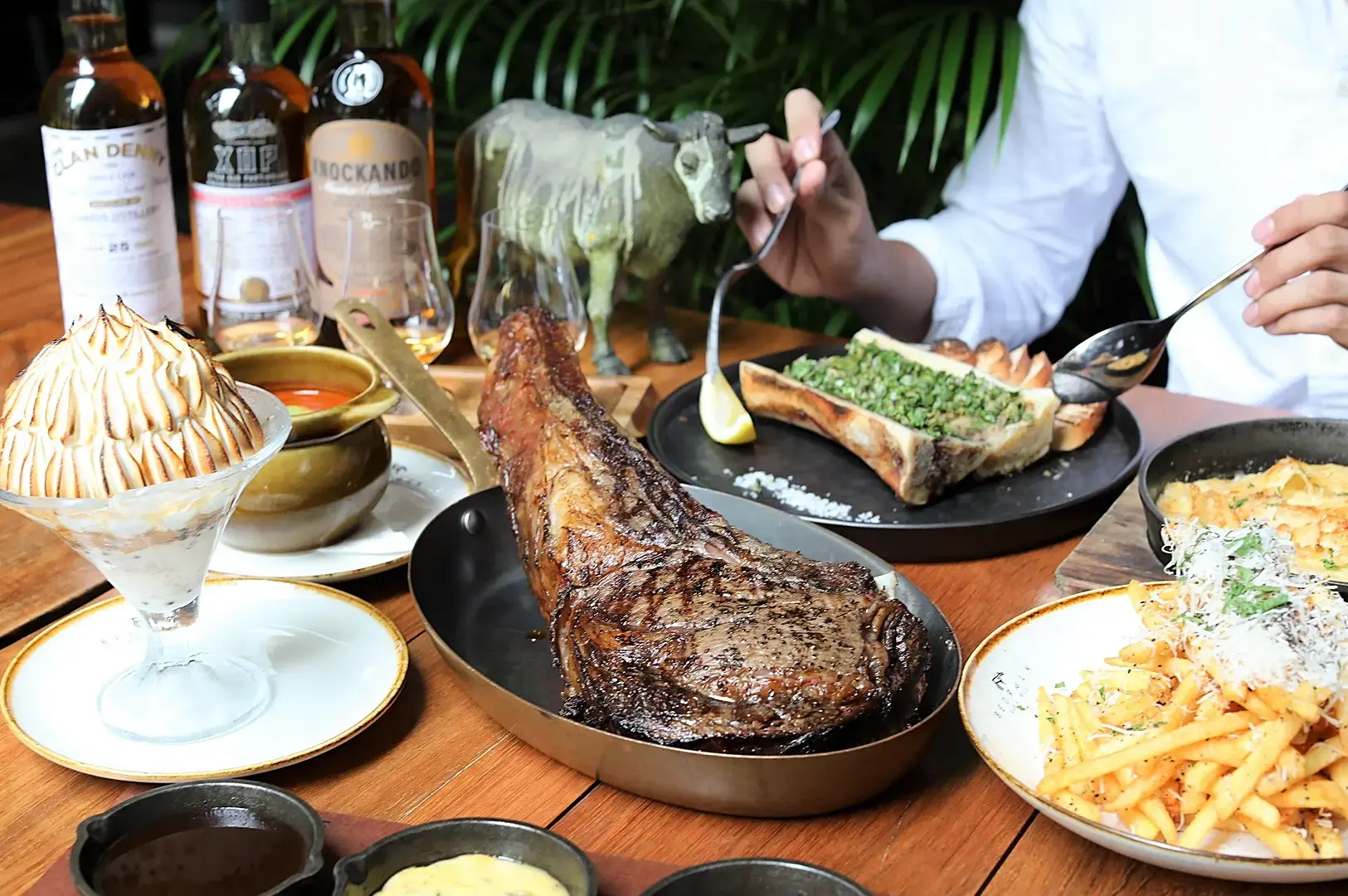 Singapore steakhouse tomahawk-style grilled steak with bone marrow, fries and premium sides