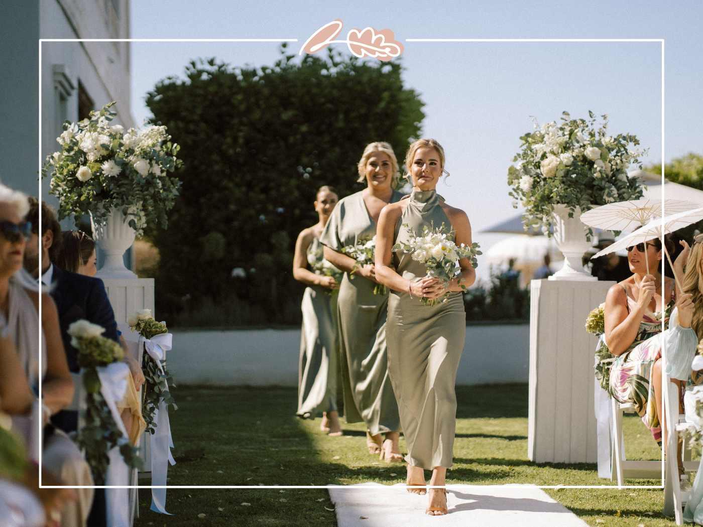 Tess's bridesmaids in sage green silk dresses walking down the aisle with white and green bouquets at Nantes Estate