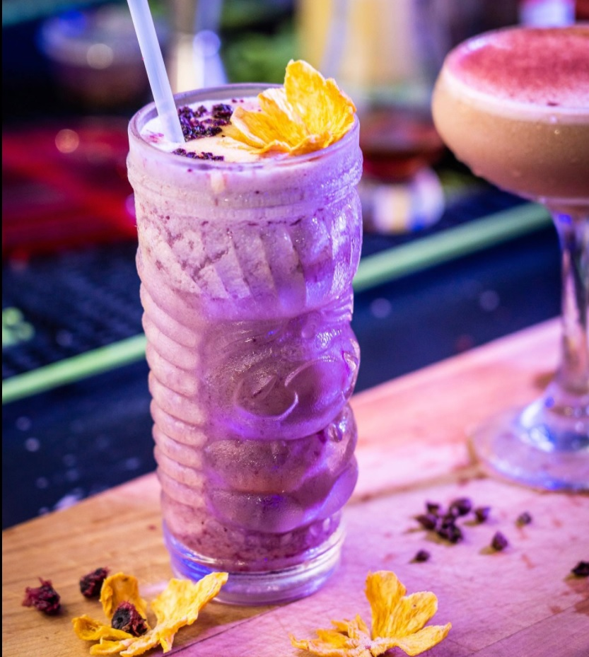 purple drink garnished with berry pieces and flower petals