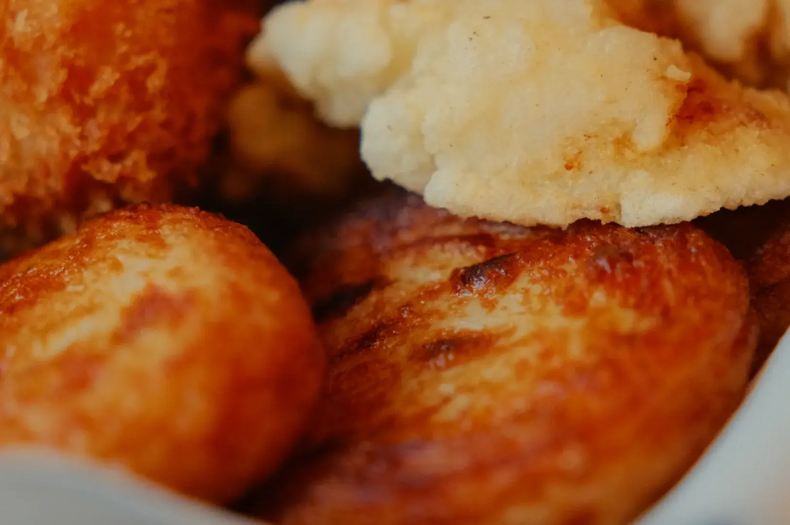 A close-up of various fried foods, including golden-brown fritters and crispy breaded items.