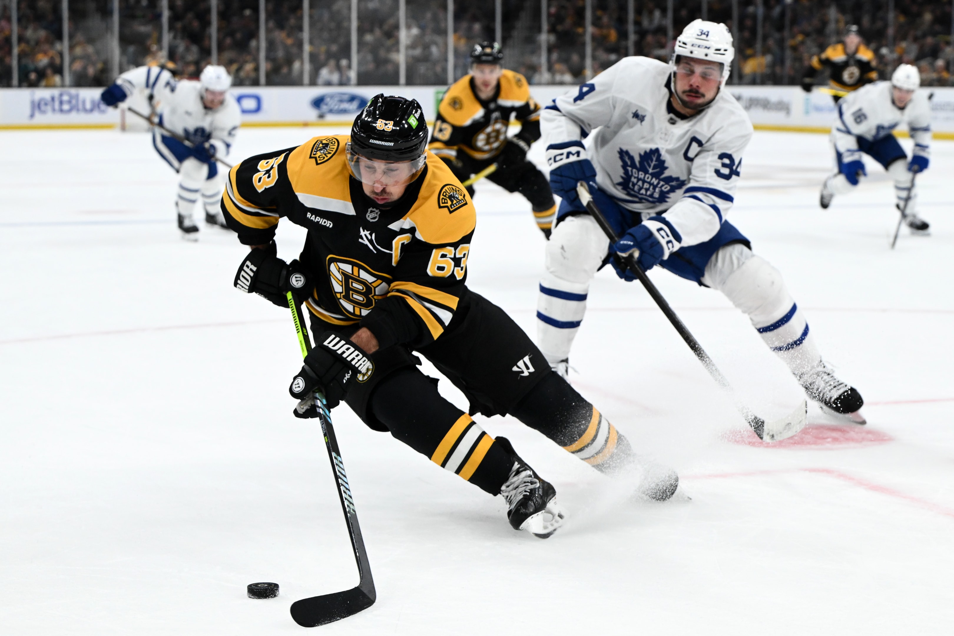 Brad Marchand of the Boston Bruins controls the puck in front of Auston Matthews of the Toronto Maple Leafs during a NHL game at the TD Garden on October 26, 2024 in Boston, Massachusetts.