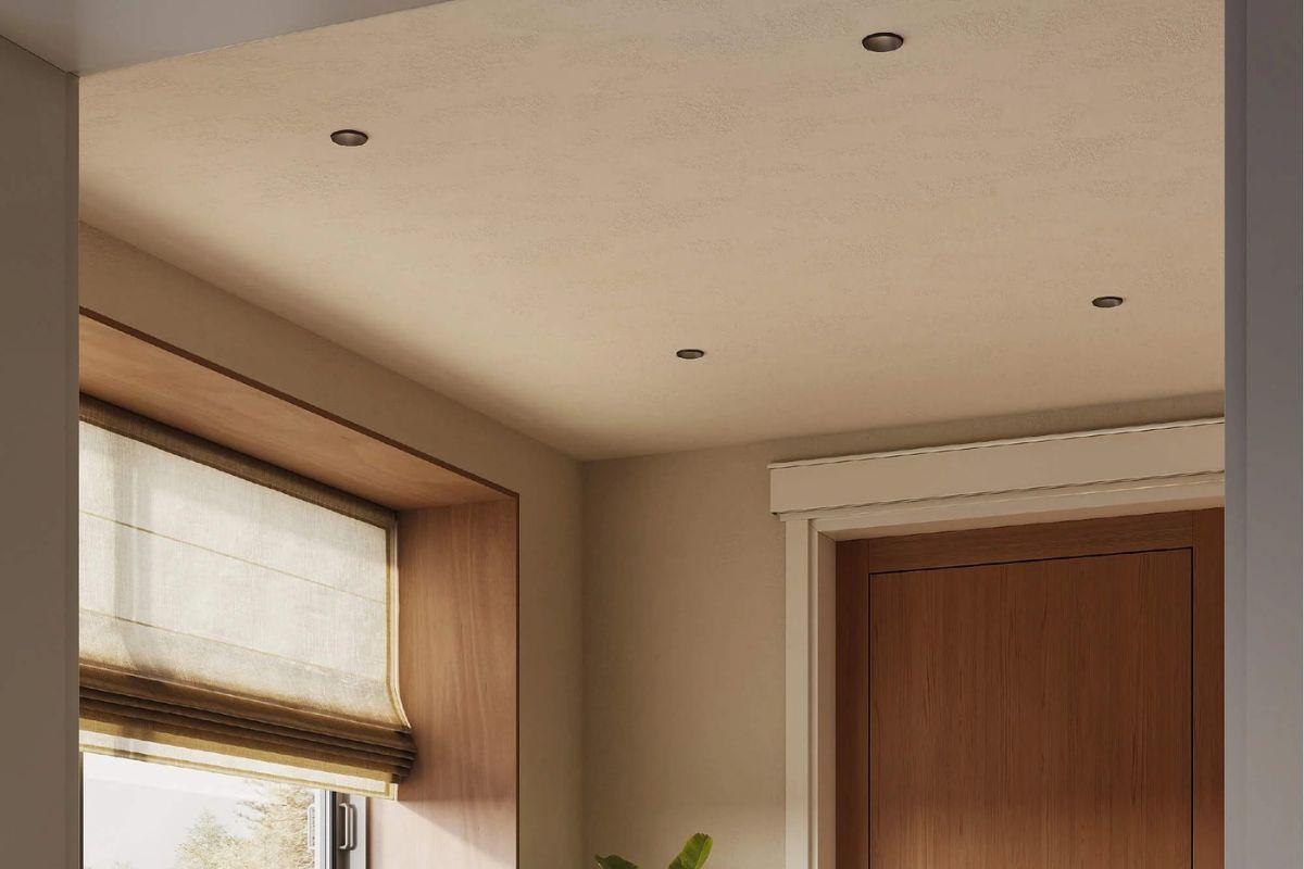 Small black recessed light fixtures installed in a warm neutral ceiling above a modern interior