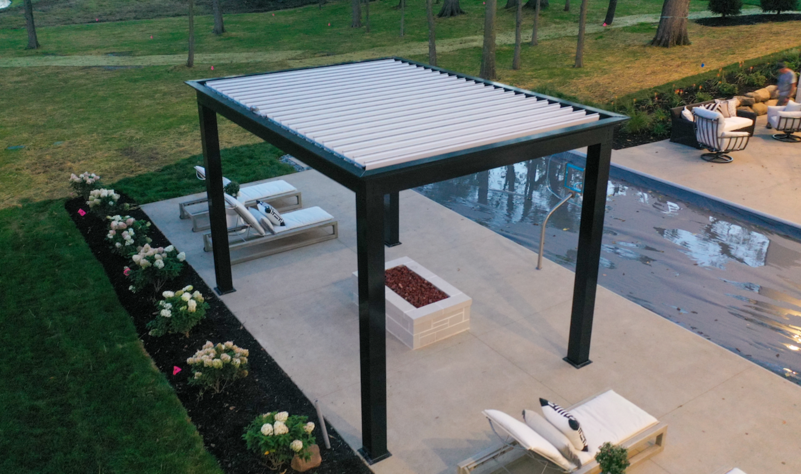 Black pergola with white louvers installed poolside.