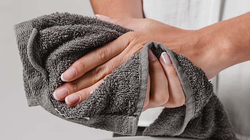 A man drying his hands with a grey microfiber towel