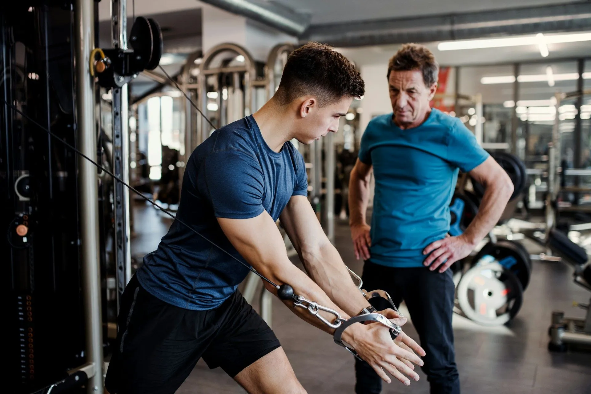 Trainer supervises an athlete performing cable resistance work in a workout routine for athletes to build strength and control.