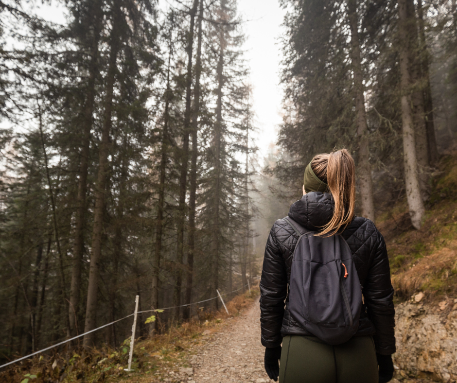 woman with proper posture wearing a weighted sack or weighted pack with a waist strap while rucking in the mountains instead of using a weight vest