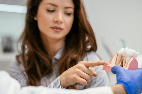 woman having an implant consultation and being shown a 3d dental model of a dental implant