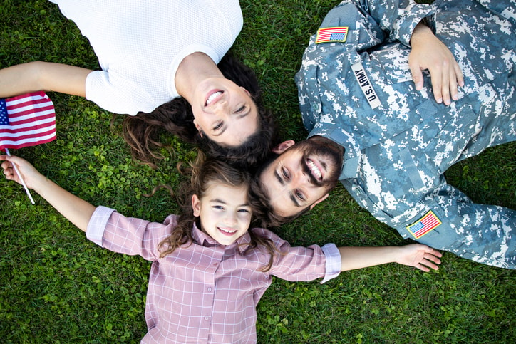 Mom, daughter, and dad, a soldier in the Army, laying on the ground. 