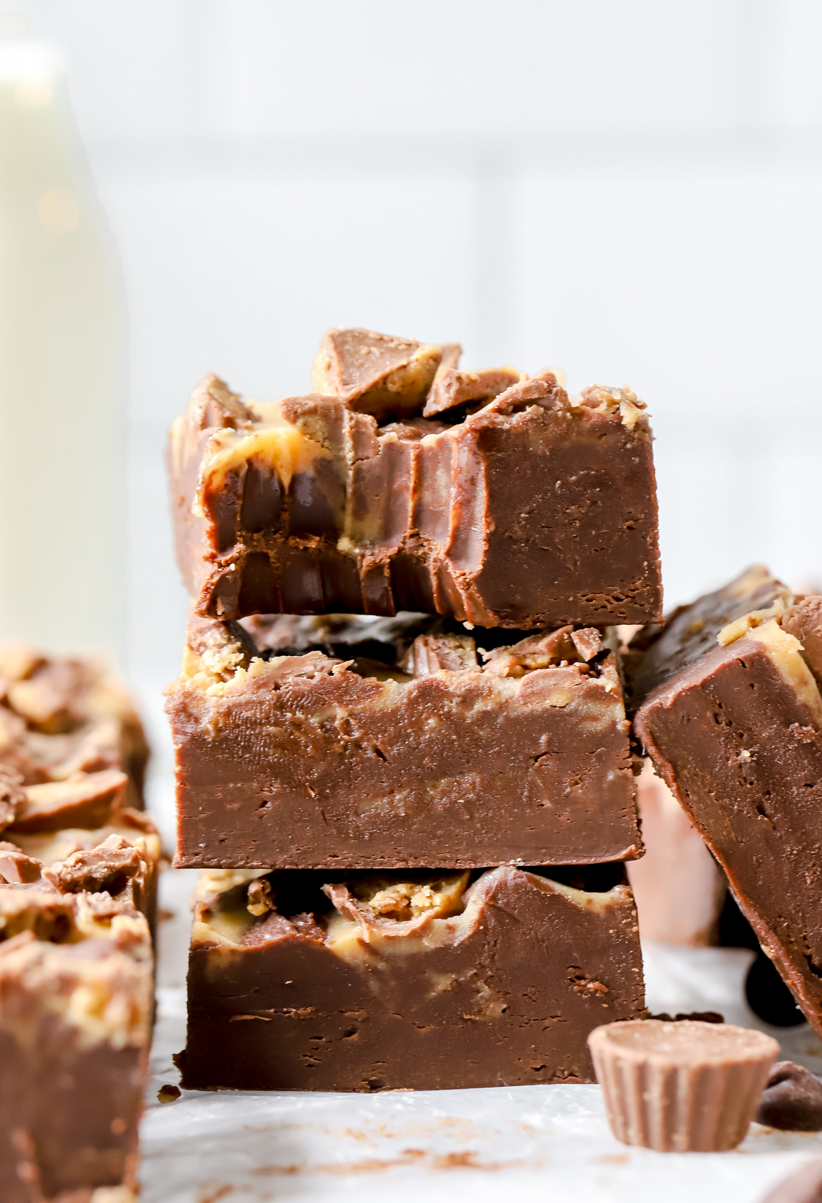 three chocolate and peanut butter fudge squares stacked, top fudge piece has a bite taken out of it