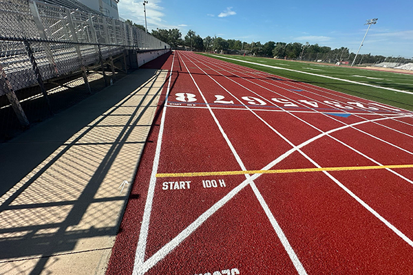 Revitalized red running track at McPherson College in KS, resurfaced with a Conica water-permeable spray coating and precise event markings for collegiate-level performance.