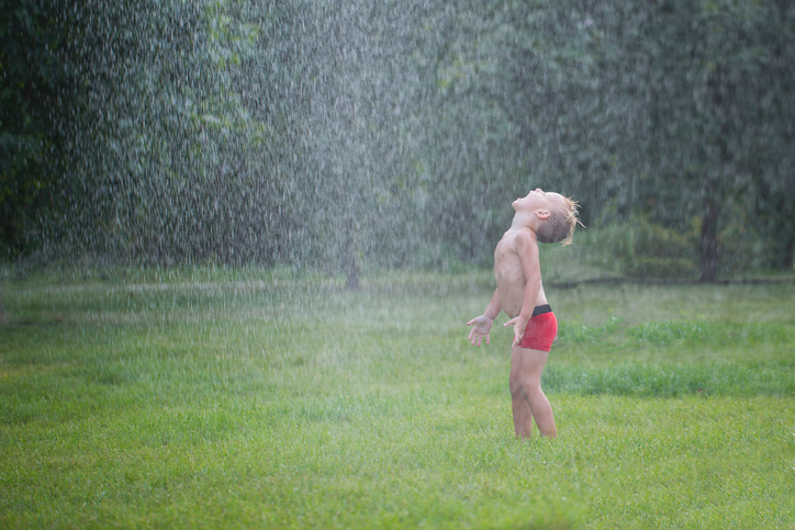 Little boy playing in the rain. 