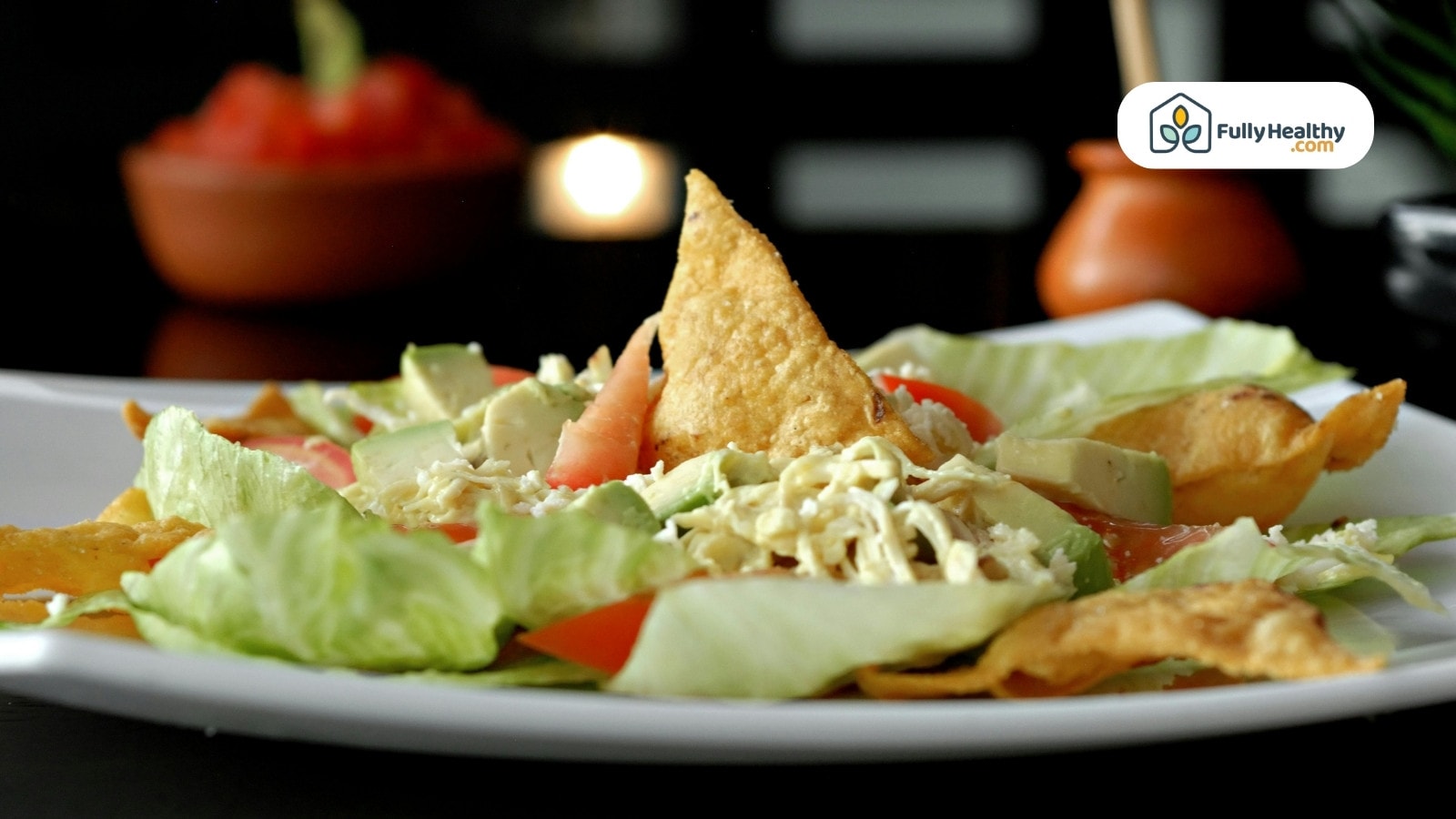Salad with tortilla chips, lettuce, avocado, and cheese.