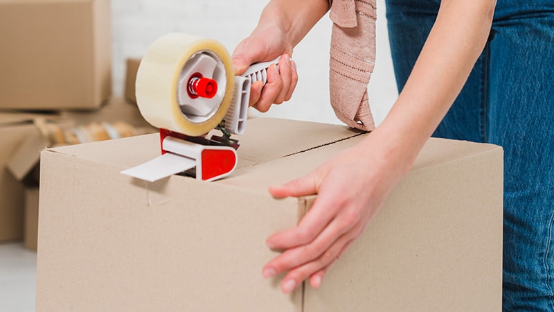 Women using tape to seal a package