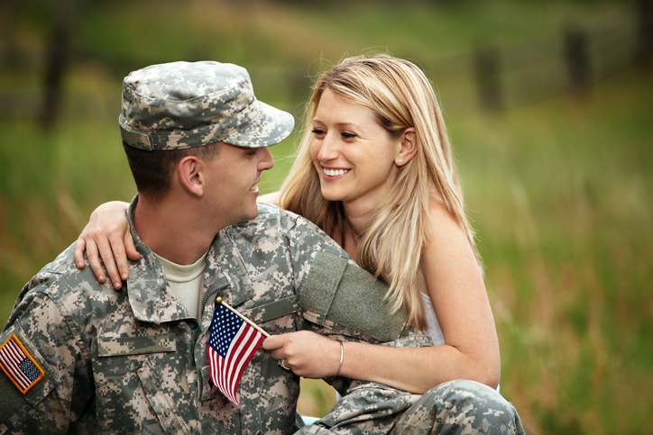 Serviceman and wife holding an American flag. 