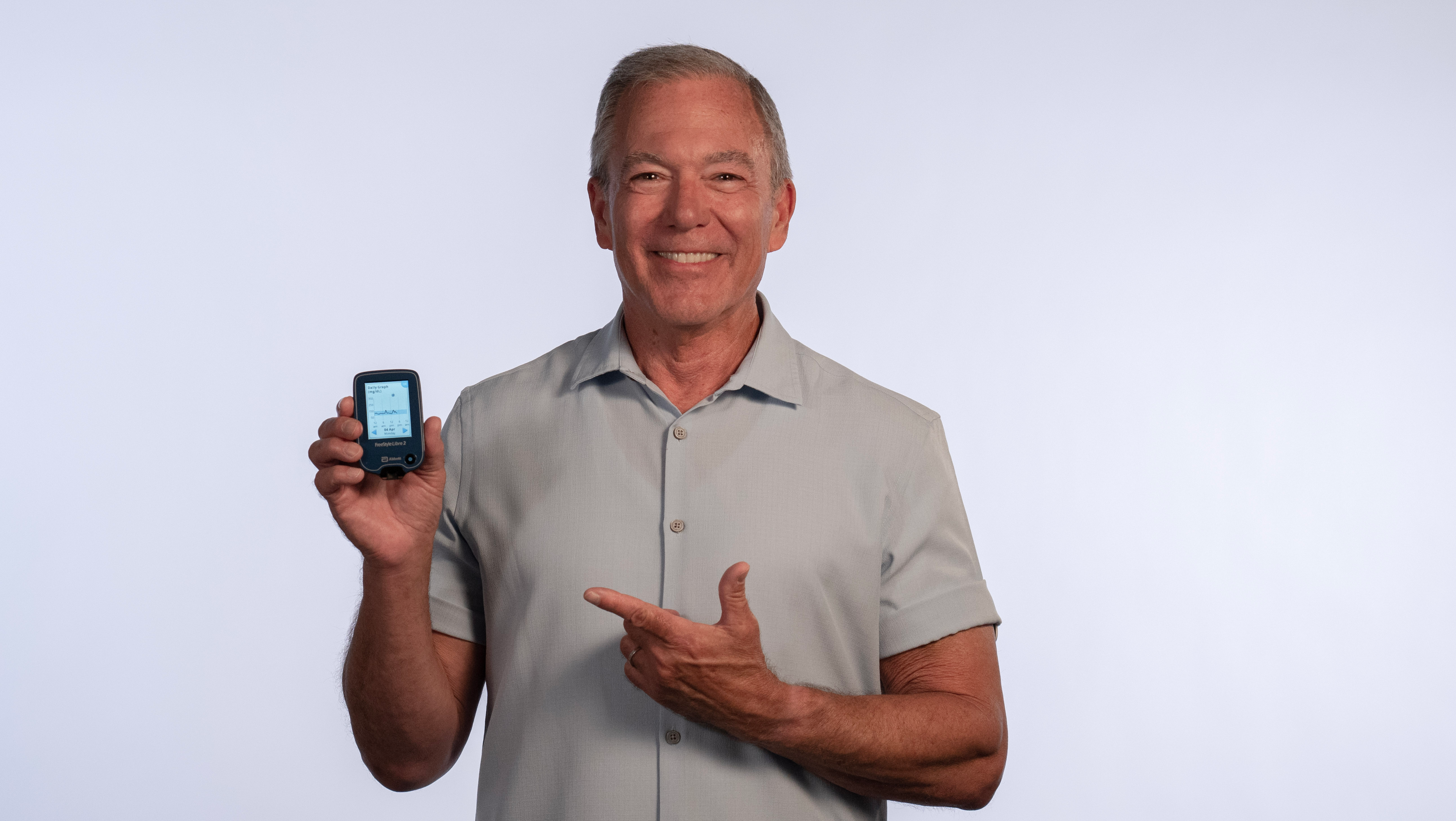 A joyful individual showcasing their CGM, a tool that assists in managing conditions like decreased insulin production and understanding reduced glucose tolerance for better health outcomes.
