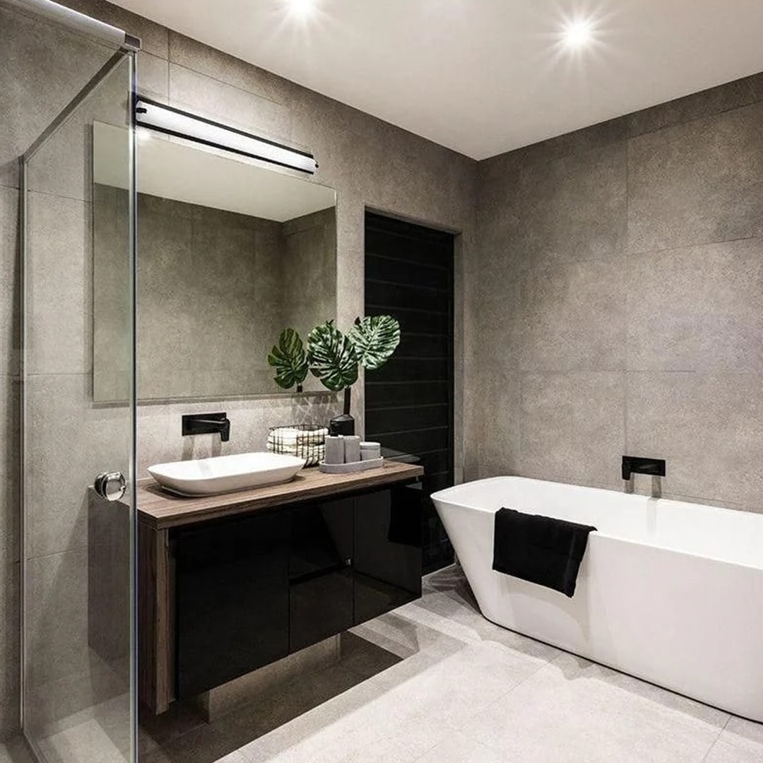Modern bathroom with sleek vanity, wall-mounted light above the mirror, and a freestanding tub, showcasing a clean mix of lighting and decor ideas.