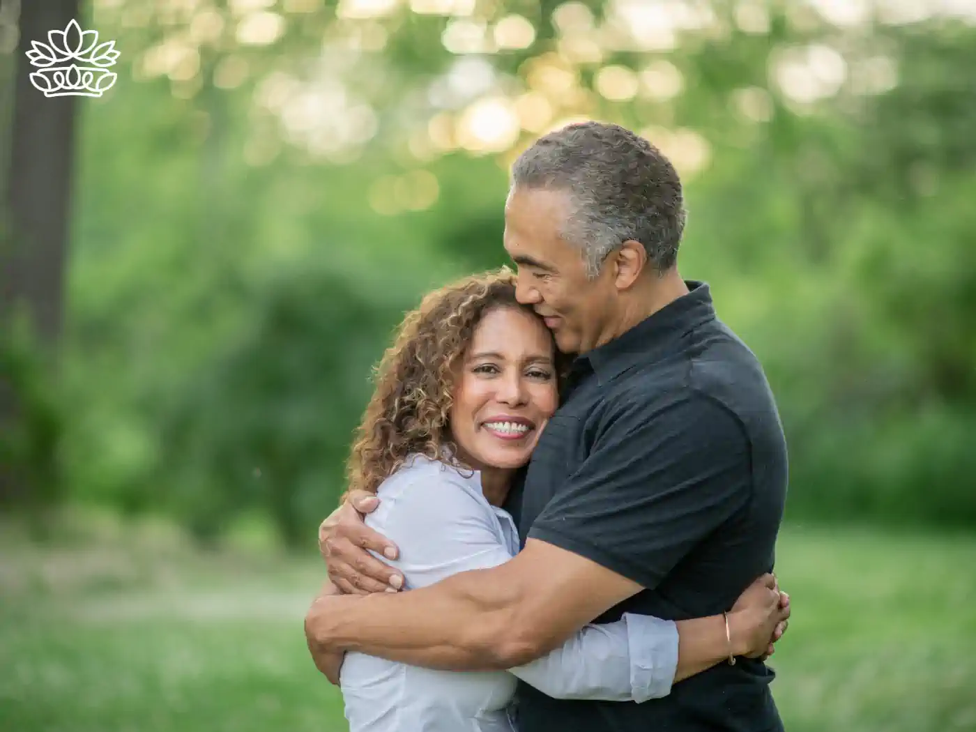 Joyful middle-aged couple embracing in a lush green park, sharing a moment of laughter and closeness, conveying happiness and love. 