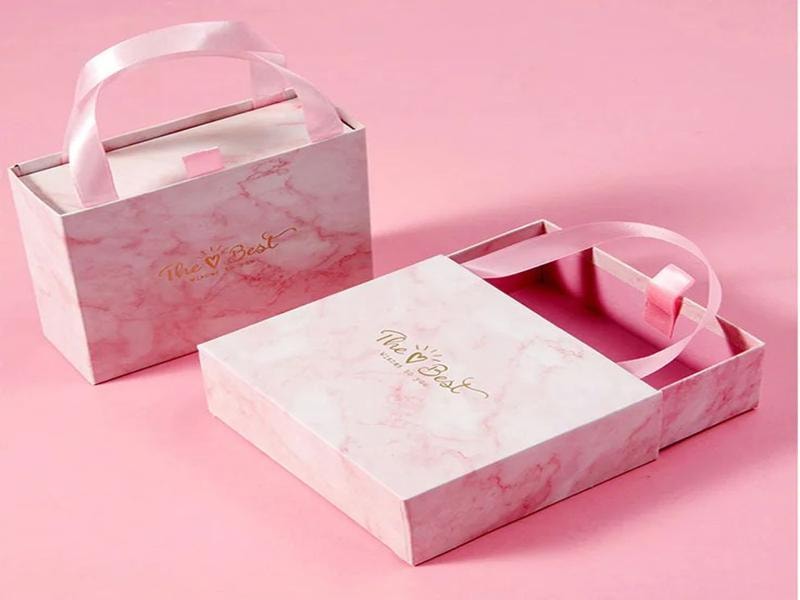 A picture of two pink subscription boxes with handles, one open and one closed, placed on a pink background.