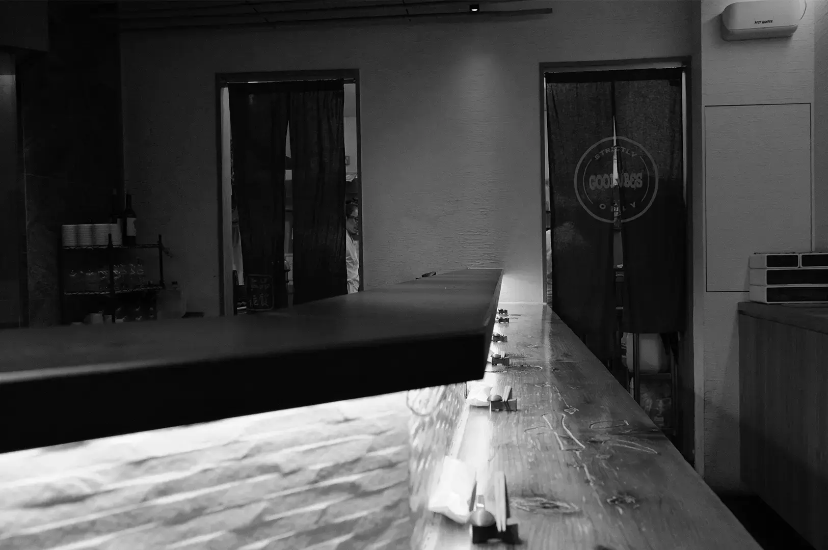Sushi To Sumi sushi counter with a long countertop and dark curtains in the background.