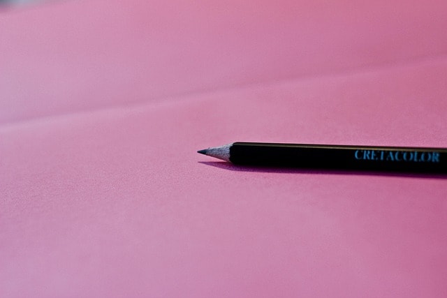 A pencil against a pink background.