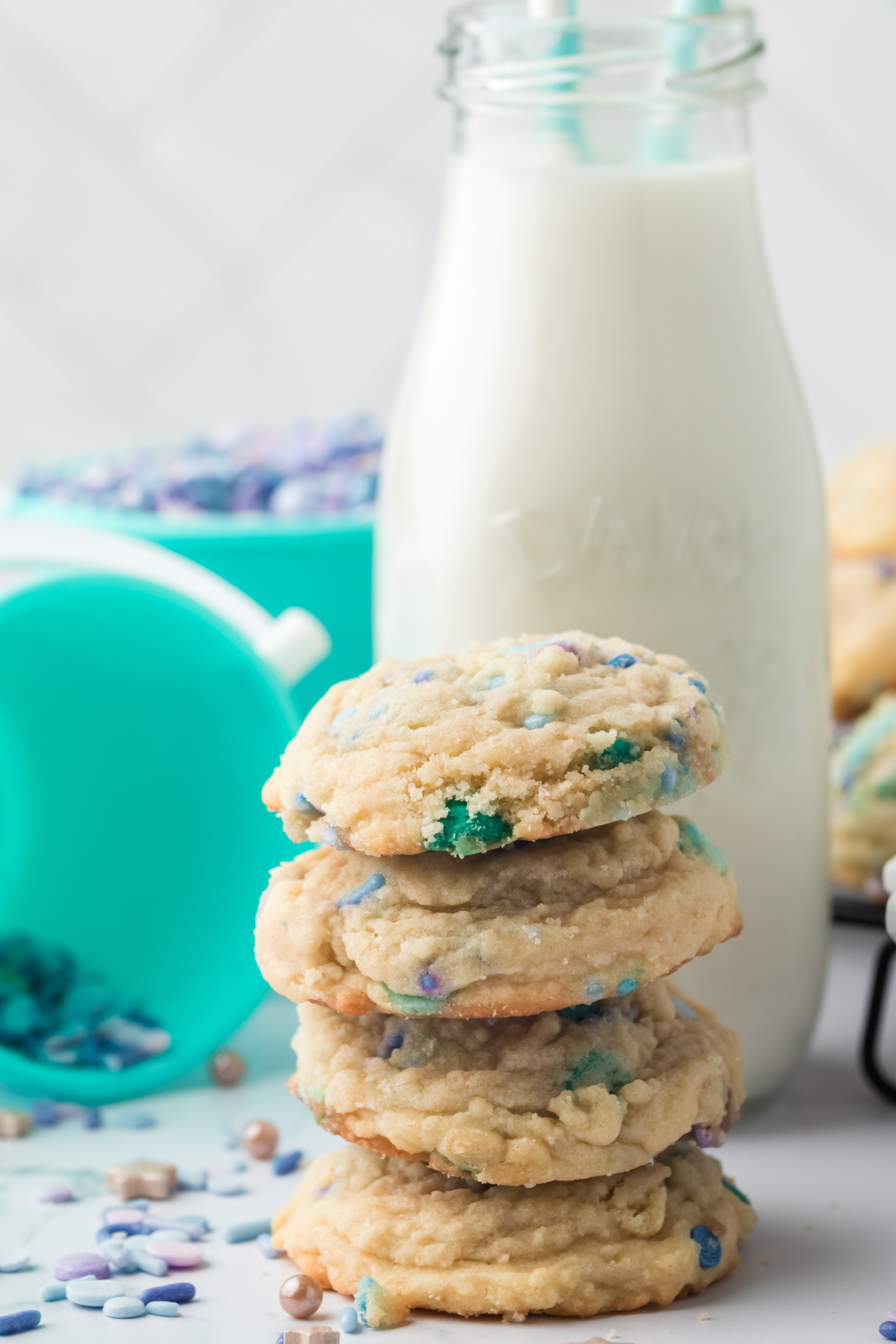 four stacked cookies in front of glass of milk