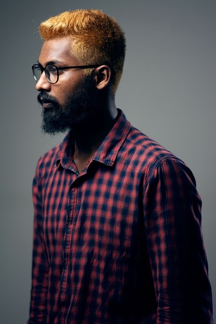 Indian man with glasses and a beard looking off to the side