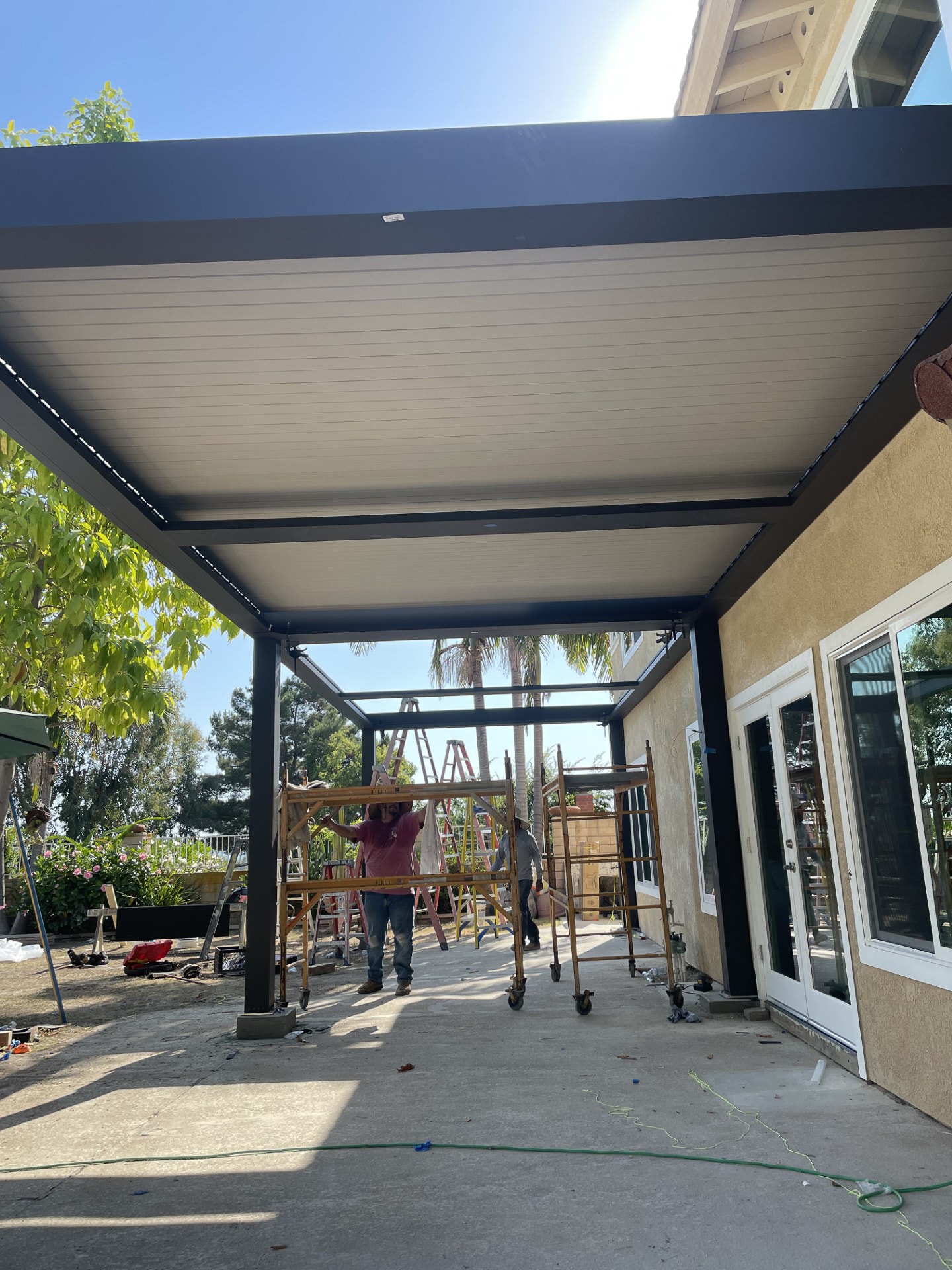 An outdoor pergola structure nearing completion as part of a larger outdoor living space remodel.