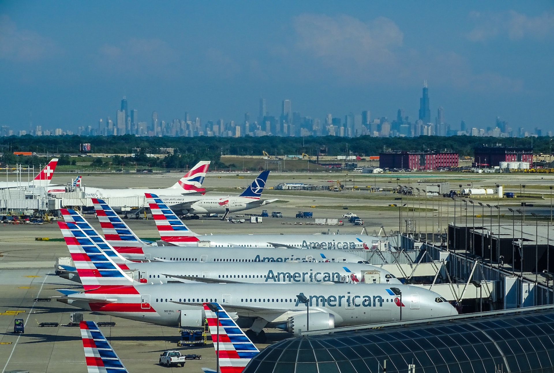 American Airlines aircraft parked at an airport of a large city with skyscrapers.