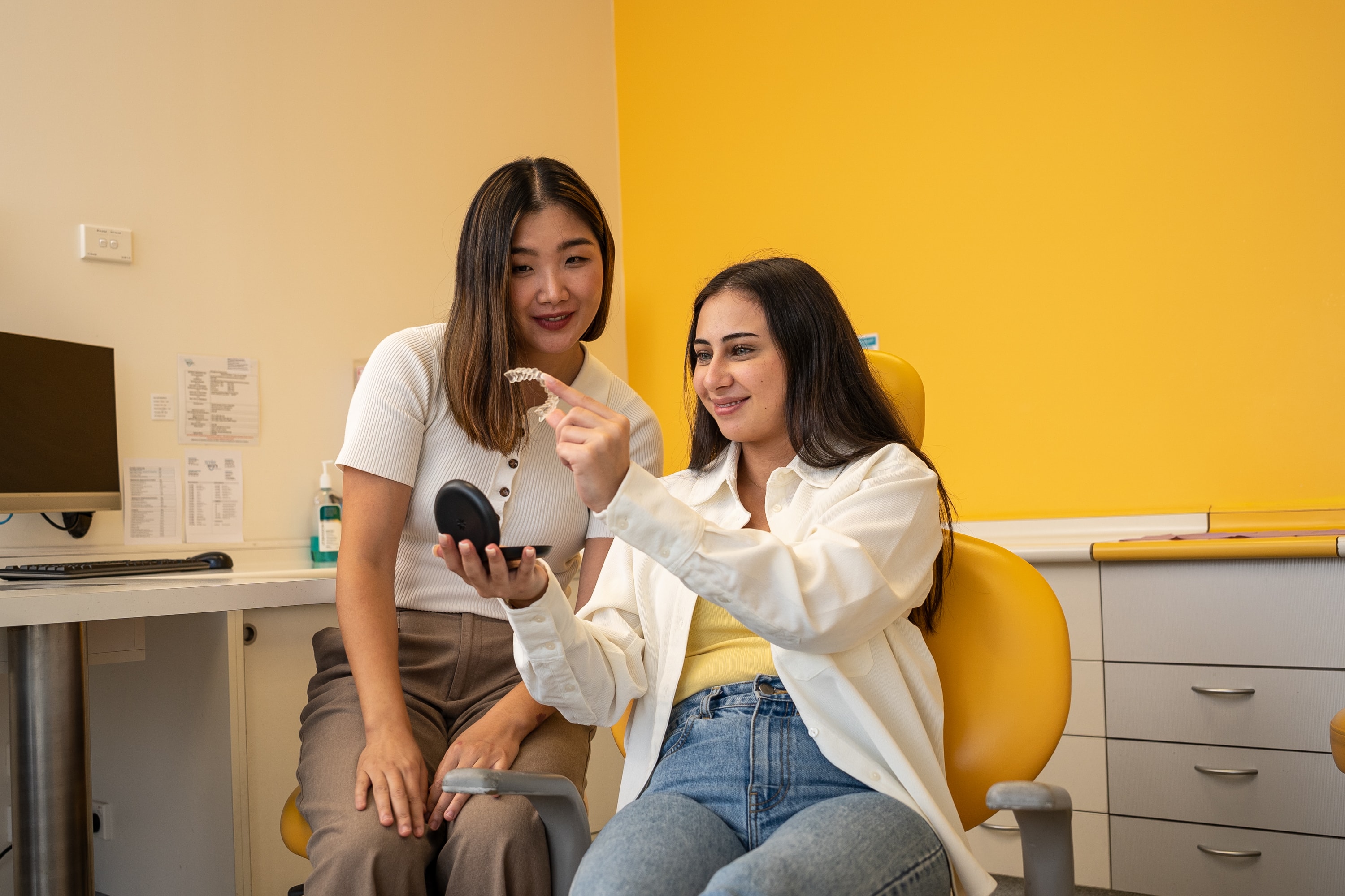 Smile Team orthodontist and female patient looking at Invisalign aligners