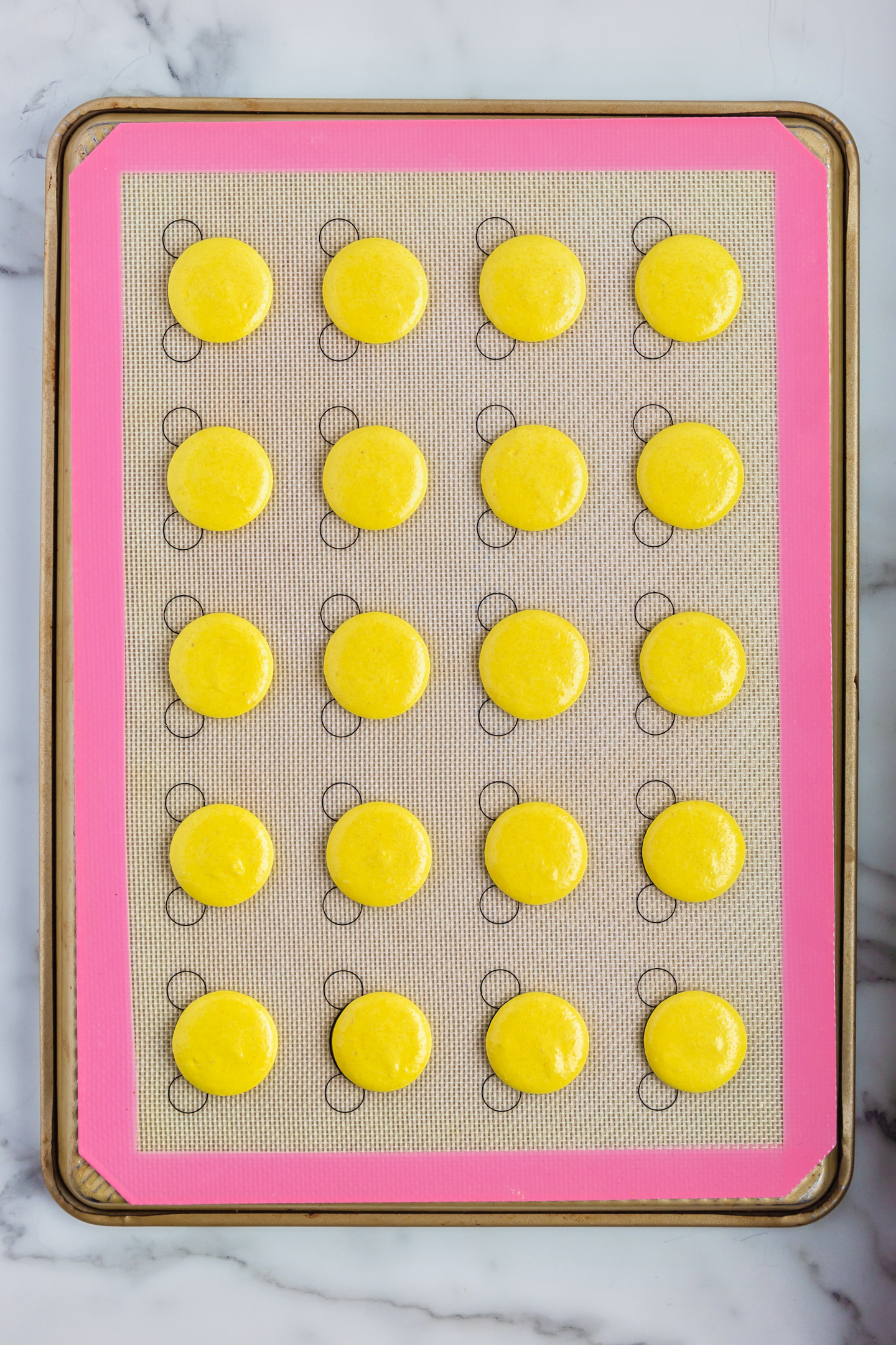 piped macaron shells on a silicone baking mat