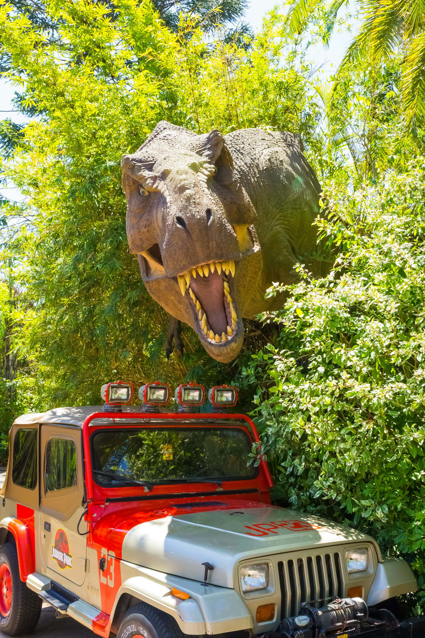 t-rex poking out of the bushes behind a Jeep