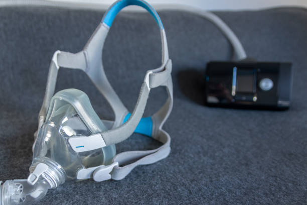 A photo of a CPAP mask and headgear with the machine behind it 