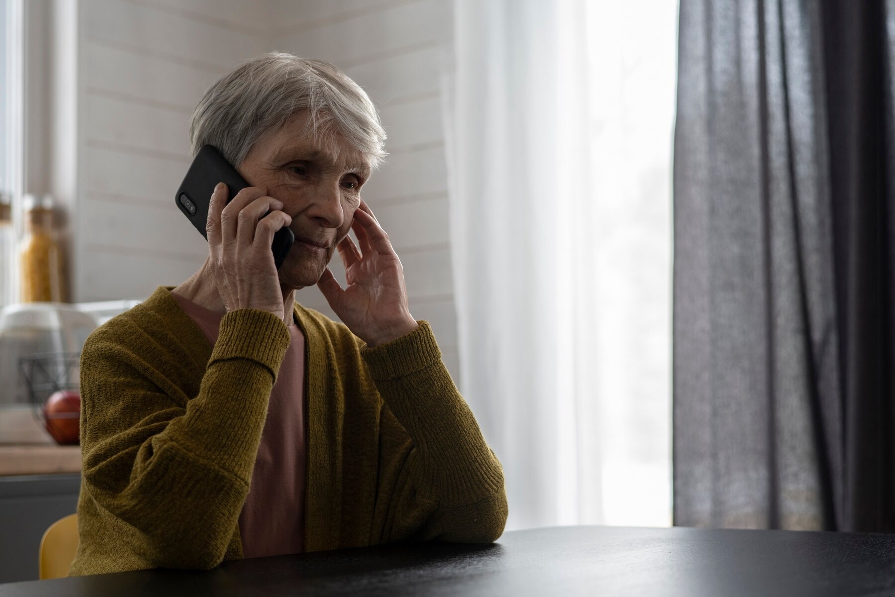 Senior woman on the phone covering her one ear