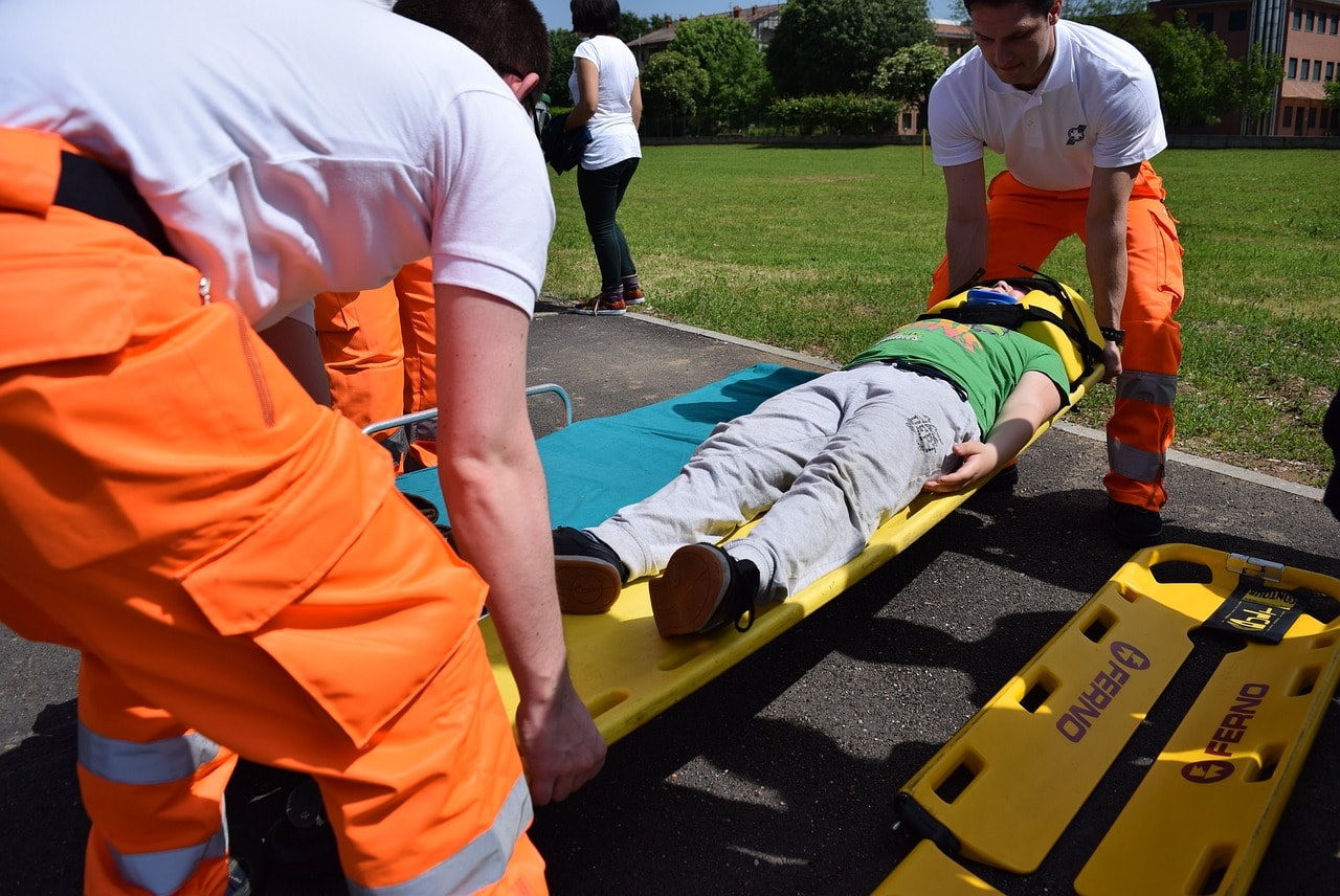 Emergency medical personnel using a scoop stretcher to transport a casualty.
