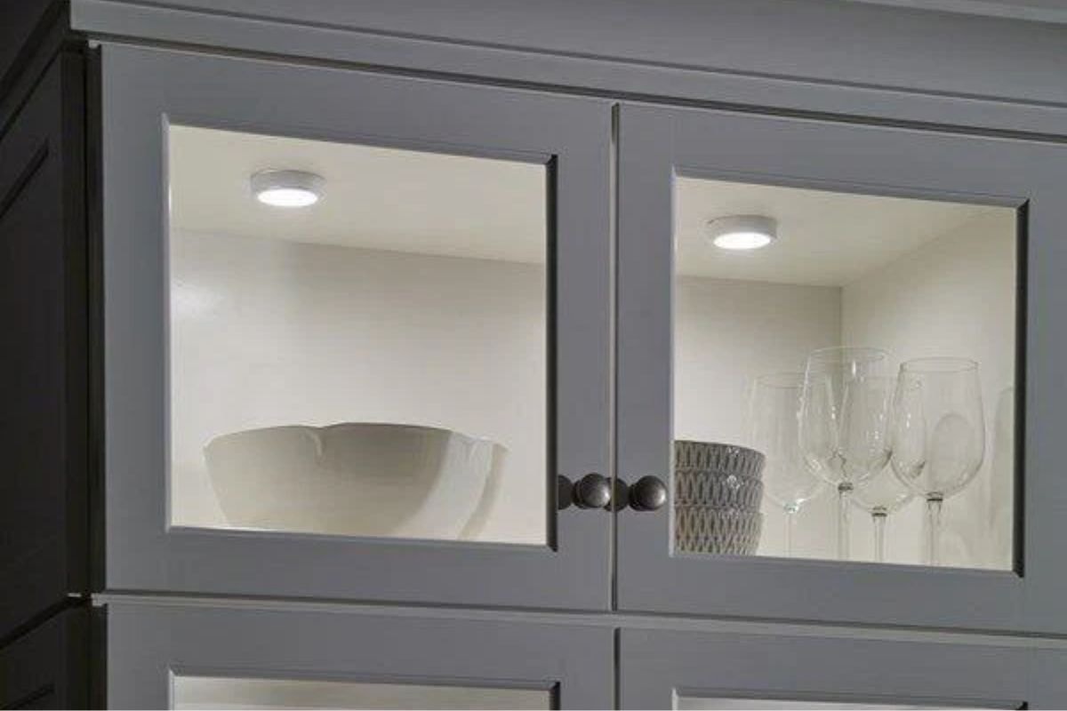 Compact Kichler LED puck light fixtures installed inside cabinets, accent lighting that highlights glassware.