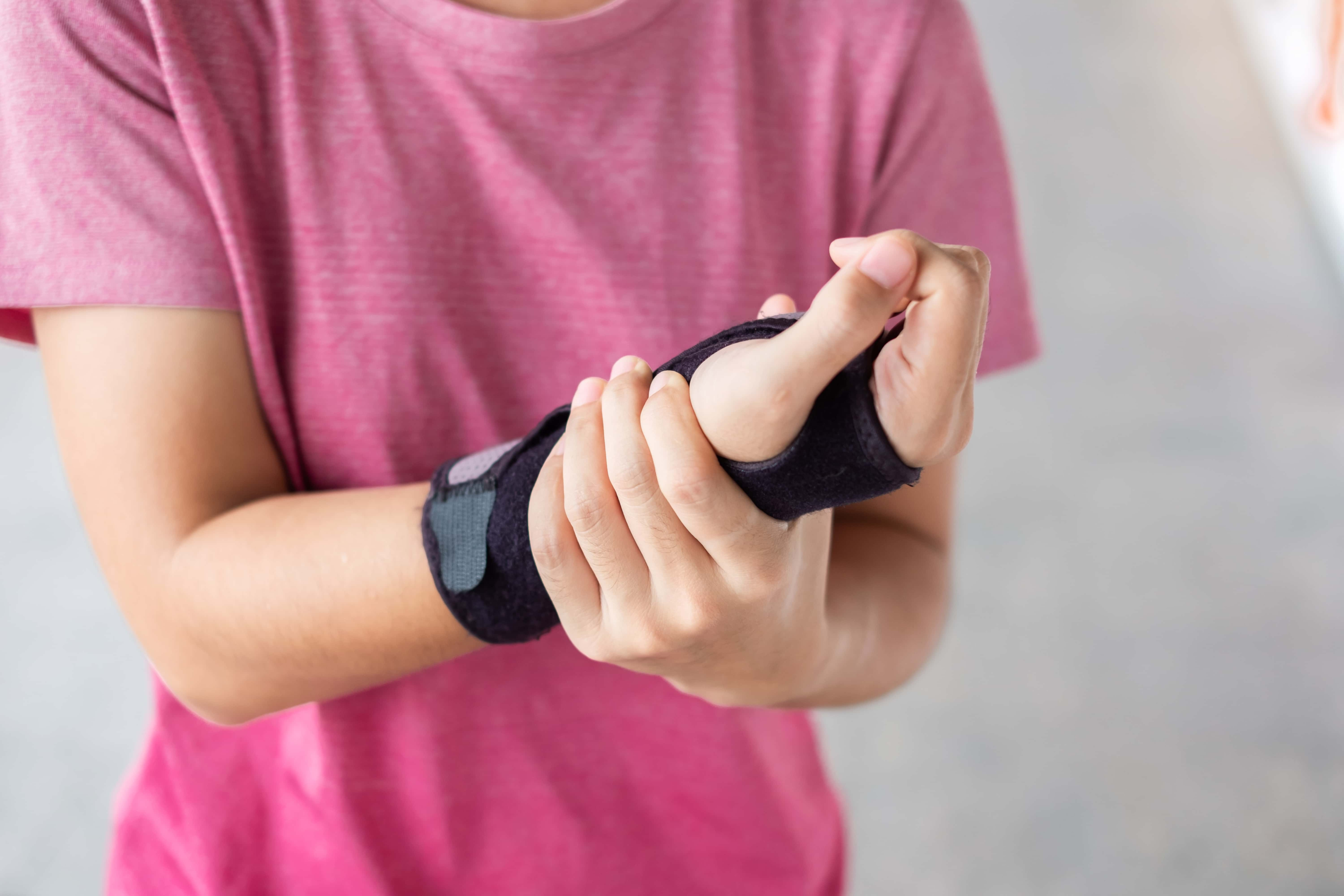 A young woman wearing a wrist guard. This protects the tendon sheaths, decrease the wrists moving and reduce swelling.