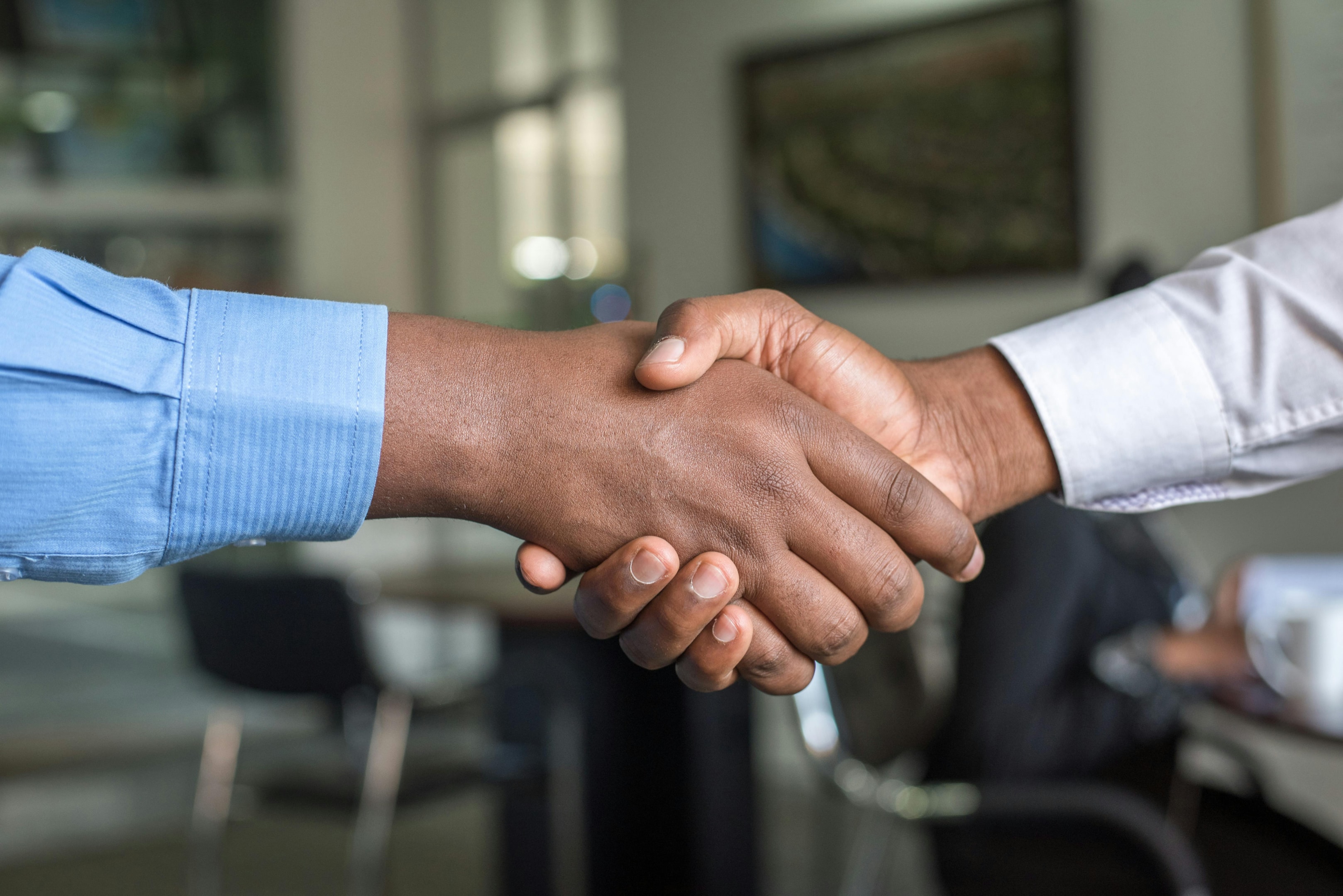 Handshake between real estate investor and motivated seller after they close on out of state deal.
