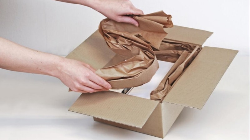 A person packaging in crumpled paper 