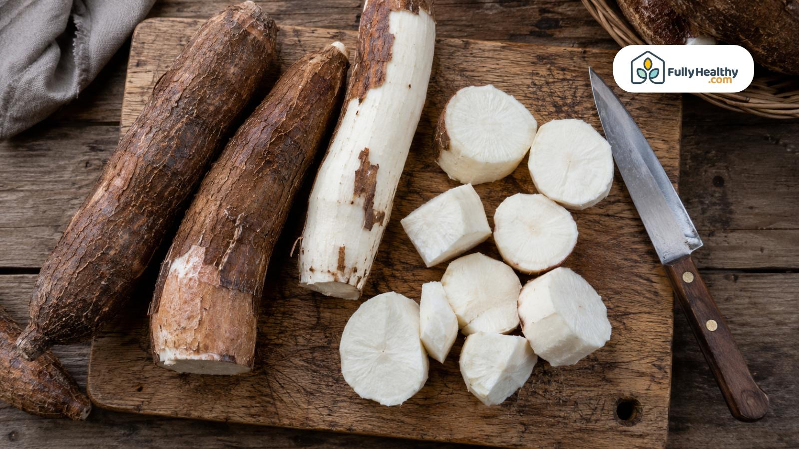 Whole peeled and sliced cassava roots arranged on a wooden cutting board