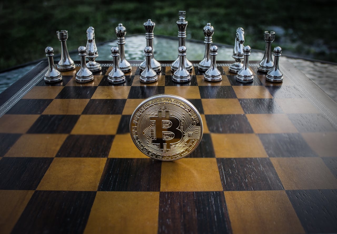 Coin with Bitcoin logo on a chessboard facing chess pieces