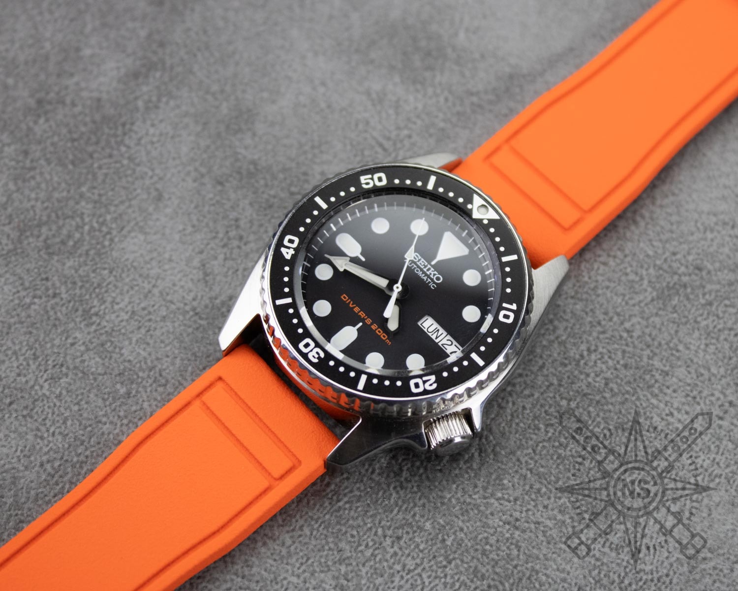 An orange rubber watch strap showcased against a neutral background.