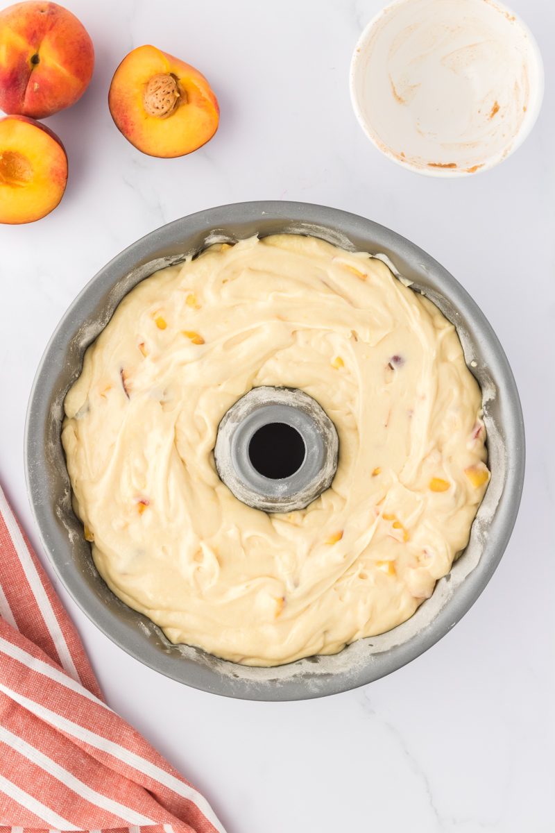 peach cobbler pound cake batter spread over topping in bundt pan