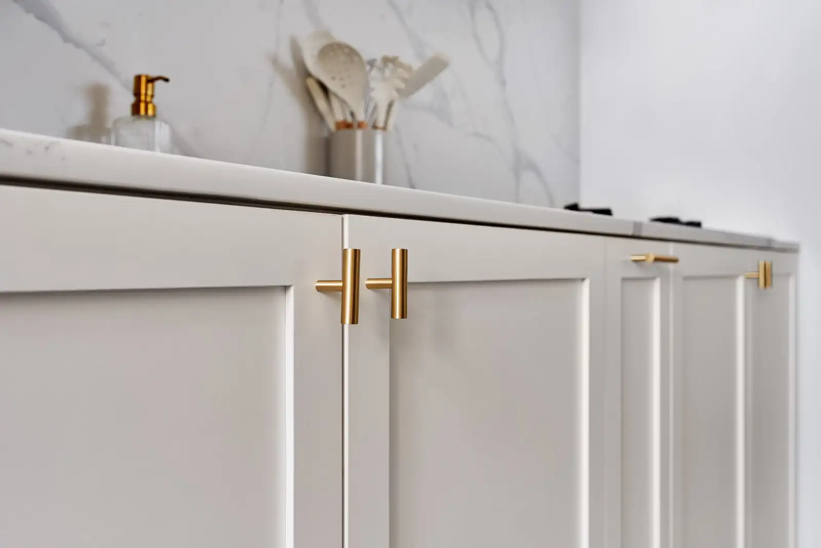 Minimalist interior design kitchen with white cabinets, brass pulls and marble-look backsplash in KL