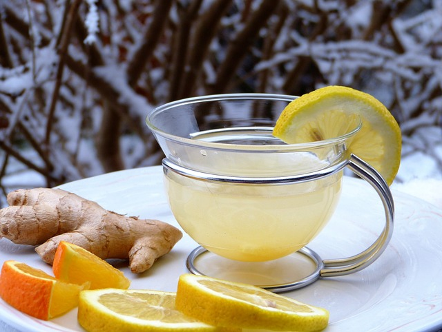 An image of a cup of warm lemon juice with lemon and orange slices and ginger as a natural remedy for throat care. 